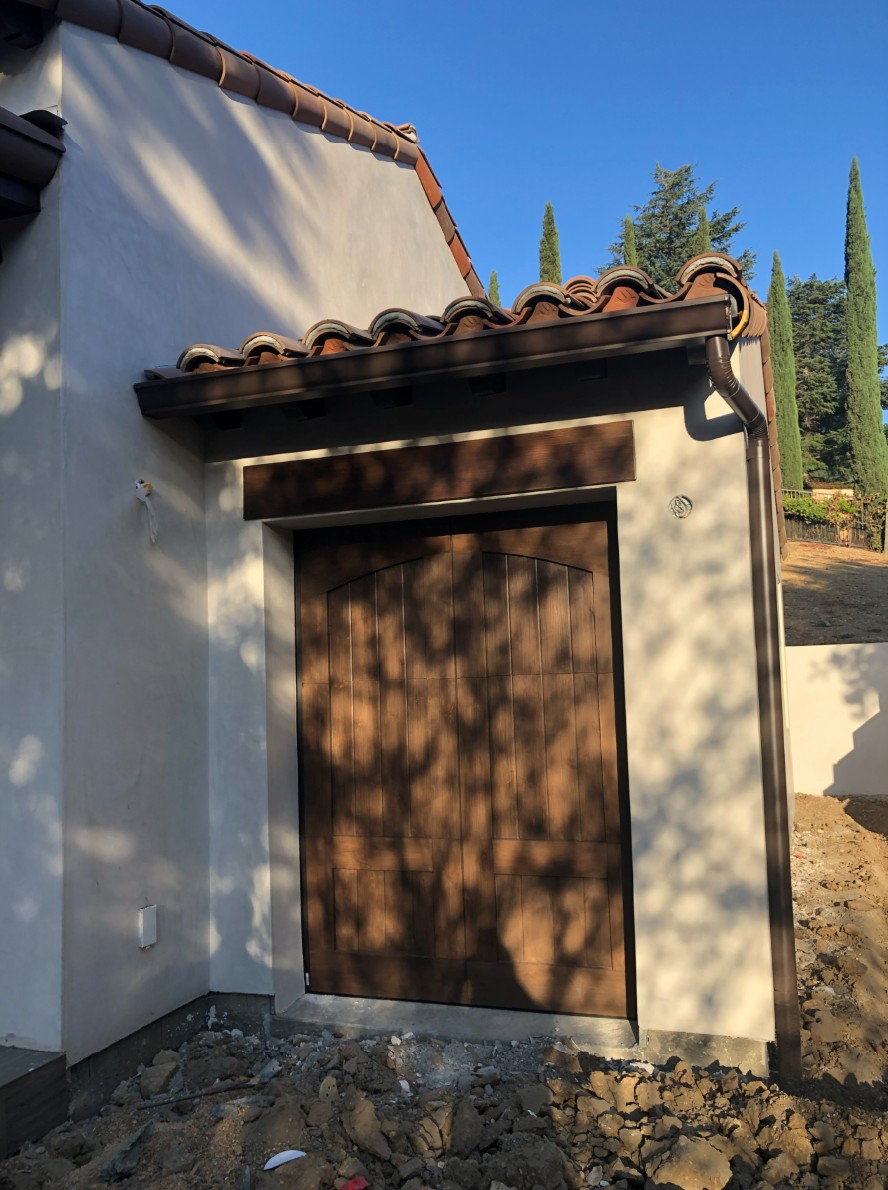 ADU garage under construction with rustic wood doors and clay barrel tile roof