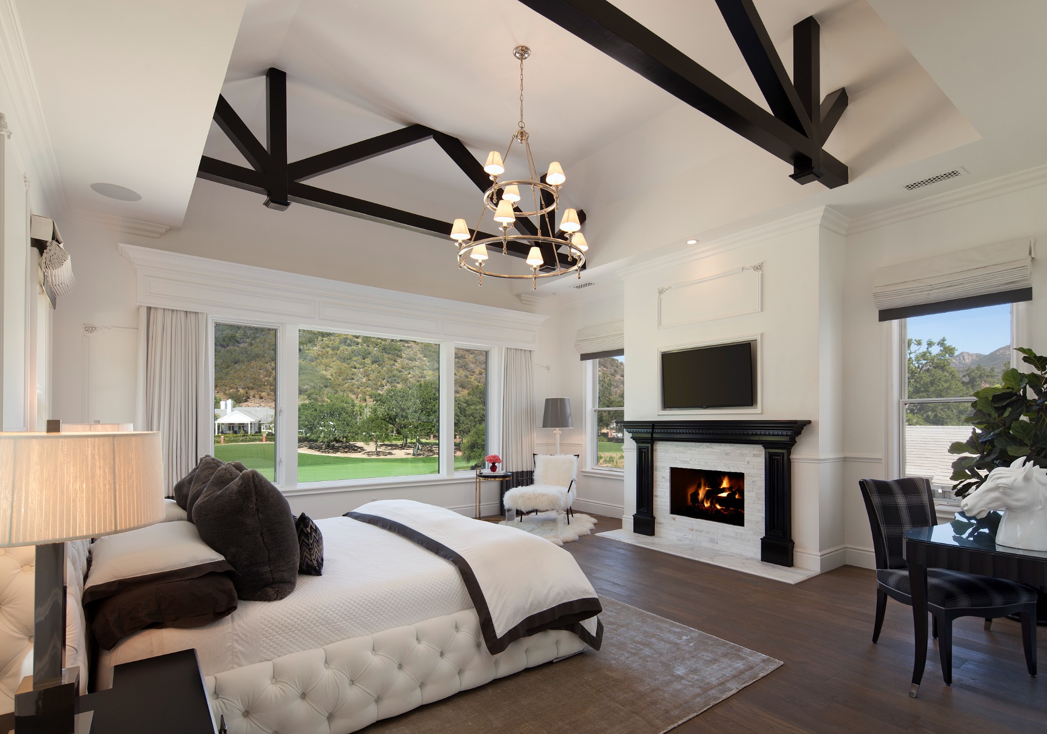 Garden Estate primary bedroom with vaulted ceiling, exposed dark trusses, fireplace, and custom paneling